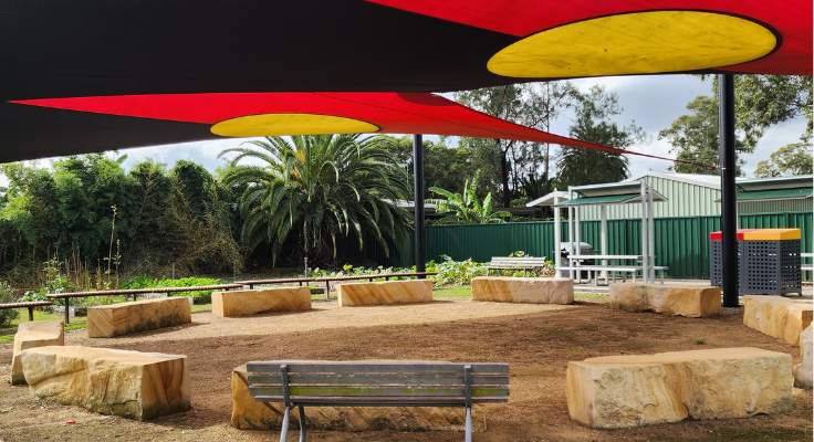 Yarning circle with Aboriginal Flag sails.
