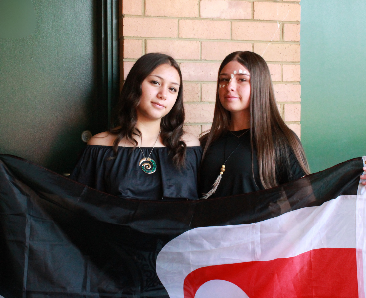 Two female students holding Maori flag