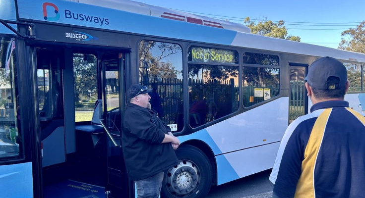 Bus driving standing in front of bus speaking to student